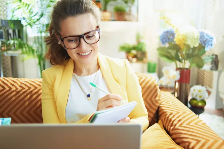 A woman sitting in front of a laptop taking notes